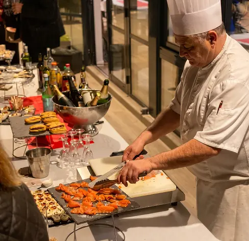 Chef tranchant un gravlax de saumon mariné devant les invités pendant l'atelier culinaire
